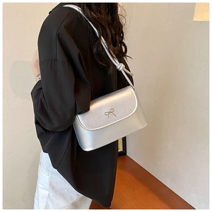 Detail showing the silver metallic crossbody bag with delicate gold bow accent
