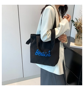 Close-up of black canvas tote bag featuring blue Beach text print and large capacity