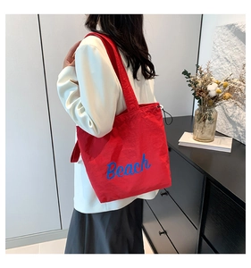 Detail of red large-capacity tote bag with blue Beach lettering for summer commuting