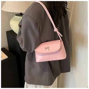 Detail of pink leather shoulder bag with gold bow ornament and knotted strap detail