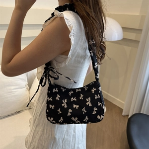 Chic black canvas hobo bag with white bow patterns and decorative shoulder ribbon