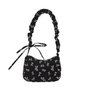 Black nylon crescent shoulder bag with white bow pattern and ruched scrunchie handle