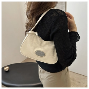 Detail of minimalist cream hobo bag with silver logo plaque on textured PU leather