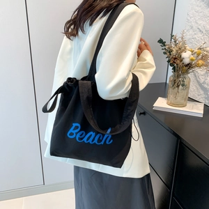 Black canvas tote bag with blue Beach lettering and drawstring closure for summer
