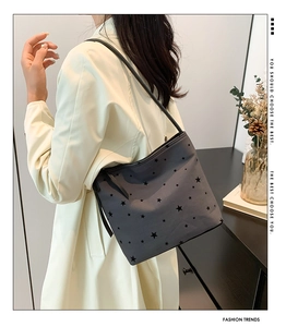 Detail view of a gray canvas tote bag with black star patterns worn over the shoulder
