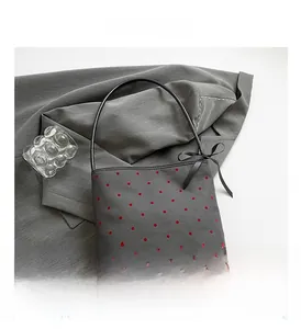 Detail of gray polka dot tote bag featuring a black silk bow and textured fabric
