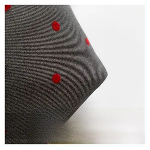 Macro shot of dark grey twill fabric with red polka dots and fine woven texture