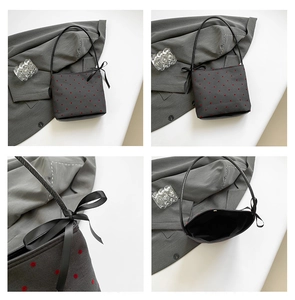 Detail view of grey polka dot tote bag with black satin bow and sleek shoulder strap