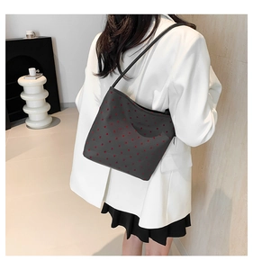 Close-up of stylish bucket bag with red heart pattern worn over a white blazer