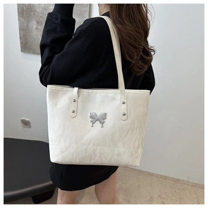 Detail of white tote bag with pleated texture and silver butterfly buckle on model