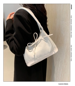 Detail of cream herringbone texture bag with leather bow and contrast shoulder strap