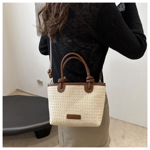 Detailed close-up of handmade straw tote bag featuring brown PU leather handles and strap
