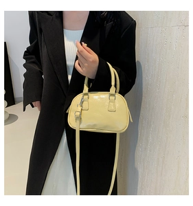Detail showing smooth light yellow synthetic leather handbag with silver hardware and shoulder strap