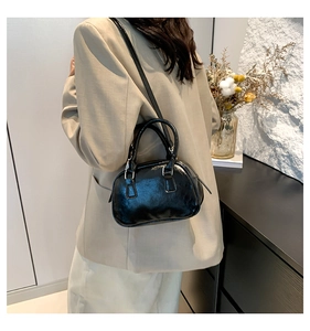 Close-up of a black glossy bowling handbag styled with a minimalist beige suit