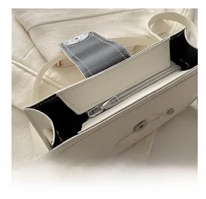 Detail view of smooth silver zipper and magnetic clasp on white leather crossbody bag