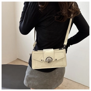 Sac bandoulière beige chic avec fermoir argenté porté par un mannequin à l'épaule