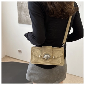 Détail d'un sac bandoulière kaki avec anneaux argentés et deux poches à rabat