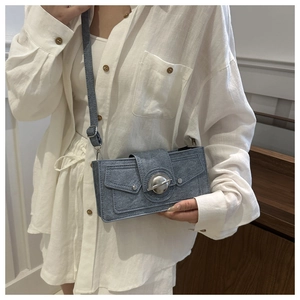Detail of blue denim shoulder bag with a stylish silver circular metal buckle