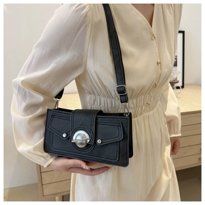 Minimalist black leather crossbody bag featuring a striking round silver buckle
