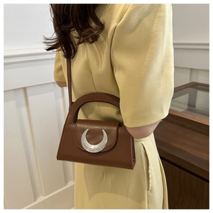 Detail of silver crescent metal clasp on brown leather handbag with polished finish