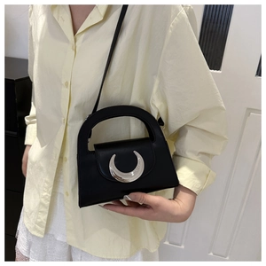 Detail of black crescent crossbody bag with silver moon-shaped buckle and leather texture