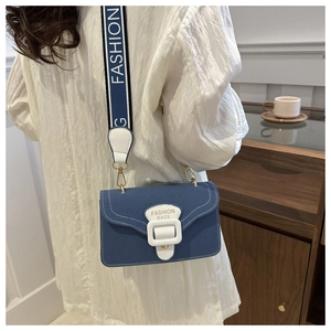 Detail of blue canvas crossbody bag with white stitching and lettered wide strap