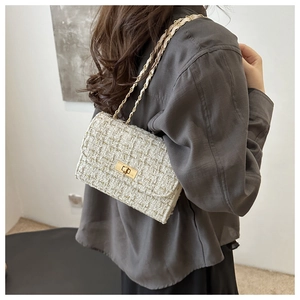 White tweed shoulder bag with gold chain strap shown on model from back view