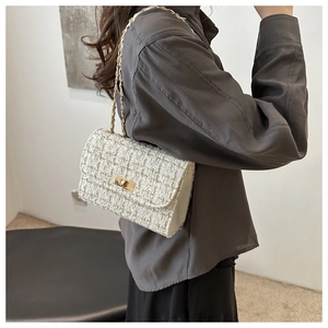 Detail view of a white tweed crossbody bag with gold chain strap on female model