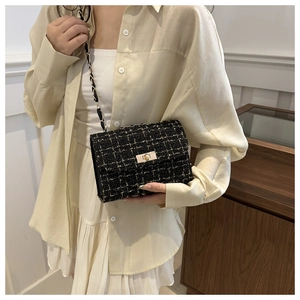 Détail d'un sac bandoulière en tweed noir avec chaîne dorée et fermoir métallique