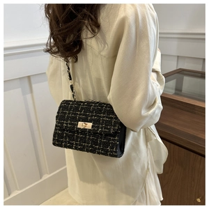 Détail de la texture en tweed et de la chaîne dorée sur un sac porté en bandoulière