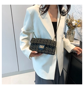 Detailaufnahme der schwarz-goldenen Tweed-Textur und des goldenen Drehverschlusses der Tasche