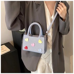 Détails du sac bandoulière bleu clair avec breloques cœur et texture tressée