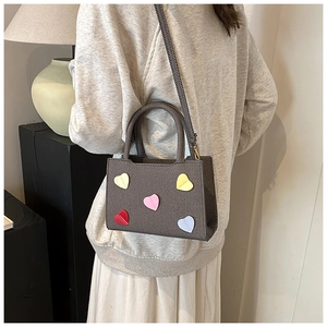 Chic grey tote bag with colorful heart patches shown being worn by a model