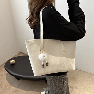 Minimalist beige cloud-texture bucket tote bag with plush charm for daily commute