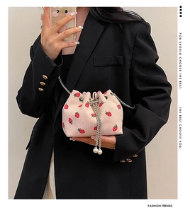 Detail of pink corduroy bucket bag featuring strawberry prints and pearl charms