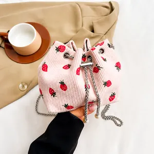 Detailed shot of pink corduroy bucket bag with strawberry prints and pearl drawstring