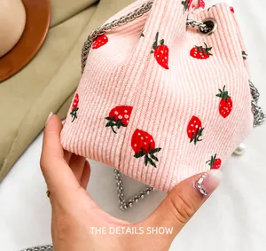 Close-up of pink corduroy bucket bag with strawberry print and silver chain strap