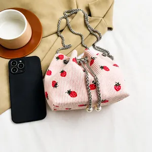 Detail view of pink corduroy strawberry bucket bag with drawstring and silver chain strap