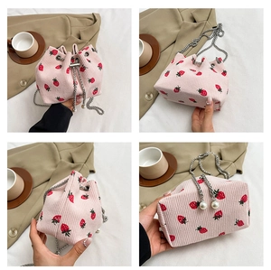 Detailed macro view of pink corduroy strawberry bucket bag with pearl drawstring and silver chain
