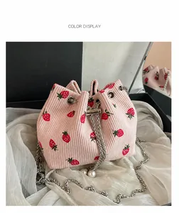 Detail of pink corduroy bucket bag with red strawberry print and silver chain