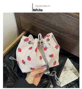 Detail of strawberry print corduroy bucket bag with silver chain and pearl charm