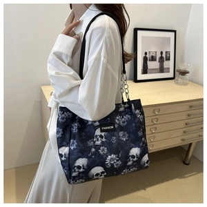 Detail of navy tote bag with white skull and blue floral print featuring a metal chain strap
