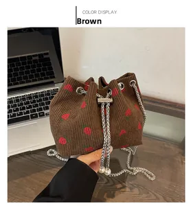 Close-up of brown corduroy bucket bag with strawberry embroidery and pearl charms