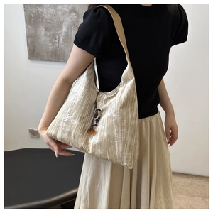 Detail of champagne gold tote bag featuring white leaf patterns and woven charm strap