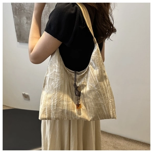 Detail of bamboo leaf pattern fabric and amber pendant on champagne shoulder bag