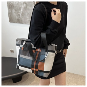 Detail of color-block geometric tote bag with wide black shoulder straps on model