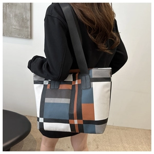 Detail of a large color-block tote bag with geometric patterns and wide black shoulder strap
