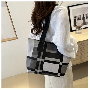 Close-up of a large tote bag with a grey and black plaid pattern and black shoulder straps