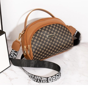 Detail view of brown semi-circular crossbody bag with vintage pattern and dual zippers