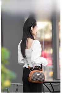Close-up of brown leather and checkered bag with a NEW FASHION printed wide strap